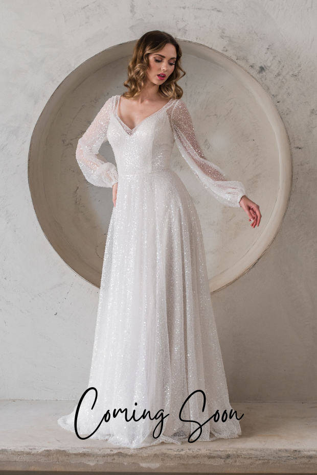 Photo shows a bride wearing a heavily beaded bridal gown by Purple Fox. Stay features allover beading creating amazing sparkle, long sleeves, and a v-neckline.