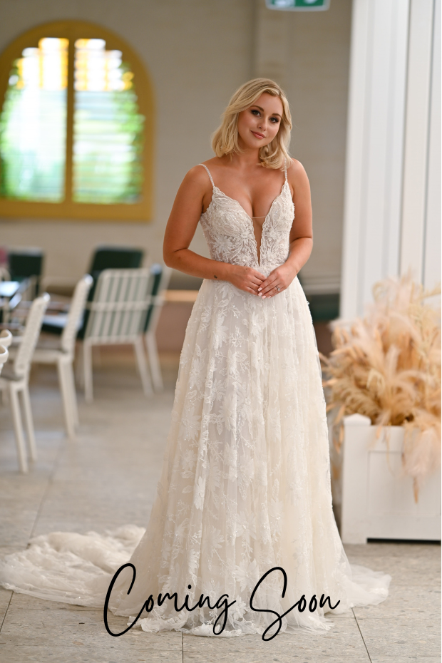 Photo shows a bride wearing an ivory lace and tulle wedding dress by Purple Fox. Young Hearts is a heavily beaded A-line bridal gown with flower lace, a plunge neckline, and beaded spaghetti straps.