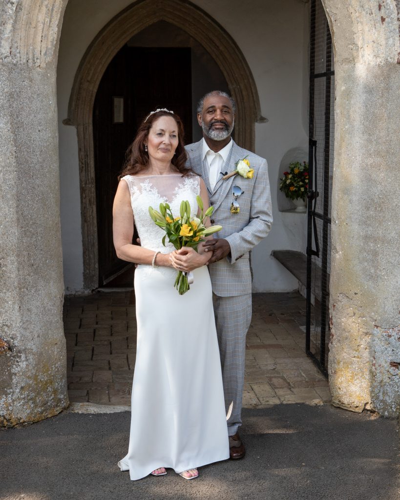 Photo of a real Lucky Sixpence bride standing with her new husband in a church doorway.