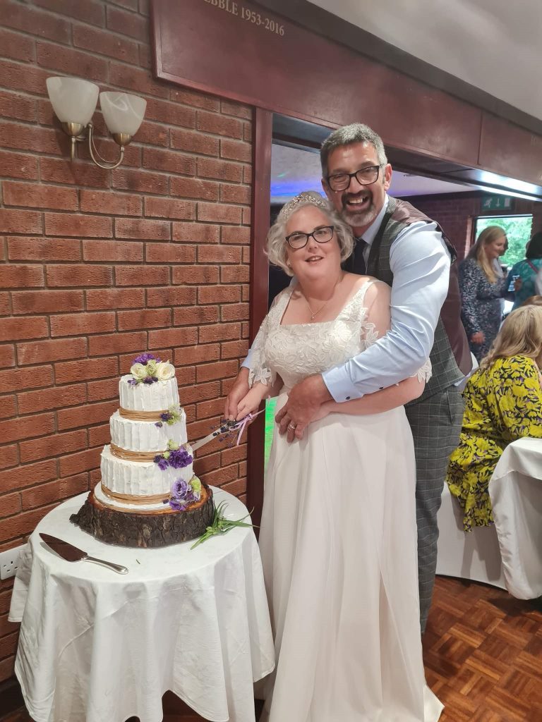 Photo of one of our real Lucky Sixpence brides and her husband, cutting their cake.